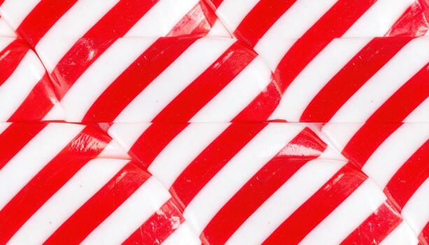 A close-up shot showcases a patterned arrangement of wrapped candies, featuring diagonal red and white stripes. The shiny, transparent wrappers create a visually appealing texture photo