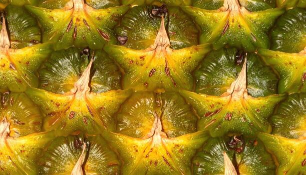 Close-up shows a detailed pattern of a fruit's spiky, textured skin in varying shades of yellow and green, creating a repeating, geometric design. Small dark spots are visible photo