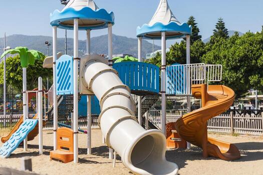 brillante y atractivo patio de recreo caracteristicas múltiple diapositivas, alpinismo áreas, y vistoso estructuras en un soleado parque. niños disfrutar al aire libre ocupaciones en el arenoso suelo, rodeado por arboles foto