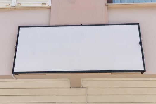 A blank signboard is mounted on a building facade. The sign is empty, indicating a space for a new advertisement or business. The setting is simple and clear photo