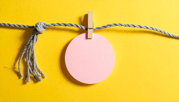 Blank Pink Circle Tag Hanging on Rope with Clothes Pin on Yellow Studio Background Copy Space for Text and Design photo