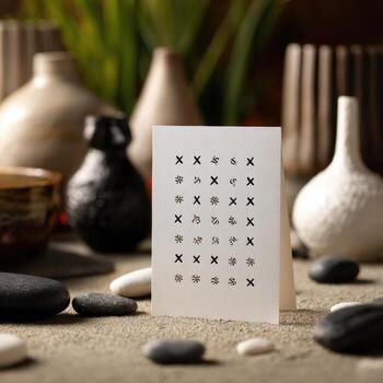A white card with repeated black X's, surrounded by pottery and stones photo