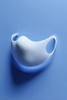 White face mask, smooth texture, on vibrant blue background photo