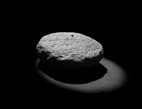 Gray stone, oval shape, lit from below, dark background photo