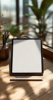 Tablet computer on wooden table, sunlit, minimalist photo