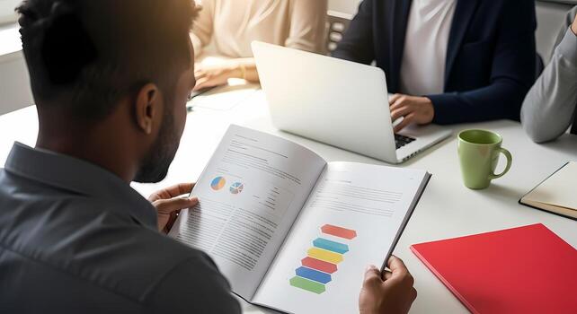 Diverse team in business meeting analyzing reports with charts and graphs on table photo