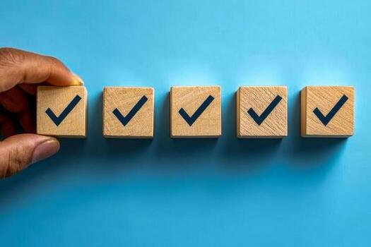 Five wooden blocks with check marks representing completed tasks on a blue background photo