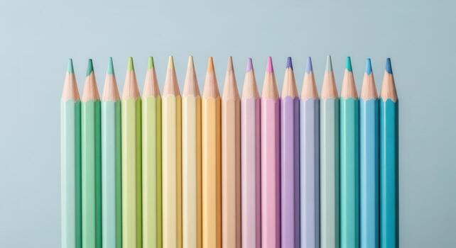 Horizontal line of sharpened pastel colored pencils on a light blue background photo