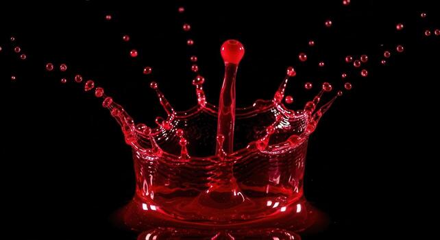 Vibrant red liquid splash forming a dynamic crown shape with scattering droplets photo