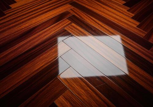 Highly polished exotic hardwood floor panels arranged in a diagonal herringbone pattern with a bright light reflection photo