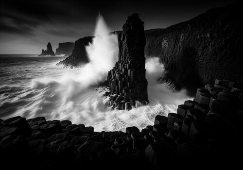 Powerful waves impacting dark basalt columns and rugged cliffs in a dramatic monochrome scene photo