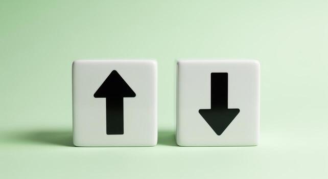 Two white ceramic cubes displaying black up and down arrows on a clean pastel green background. photo