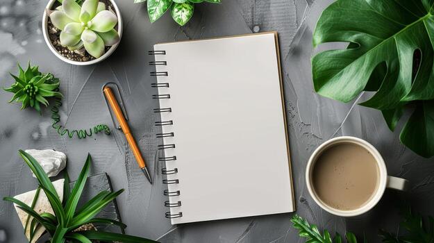 Blank Notebook Surrounded by Green Plants and Coffee Mug on Gray Surface photo
