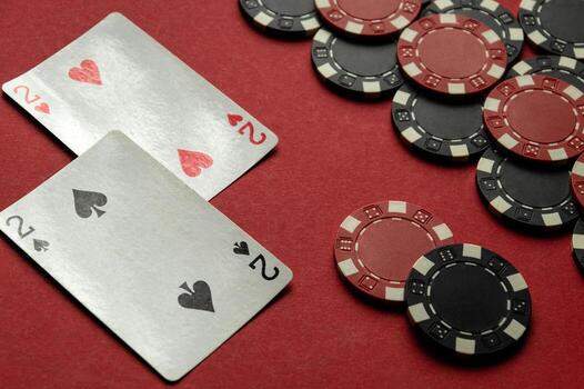 Two playing cards showing pairs of twos rest on a red felt table alongside scattered poker chips, creating an engaging atmosphere for card players photo