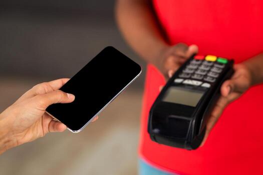 Woman paying for purchases using modern easy nfc technology, holding smartphone with empty blank screen in hand closeup. Card reader machine making payment transaction with cashless contactless method photo