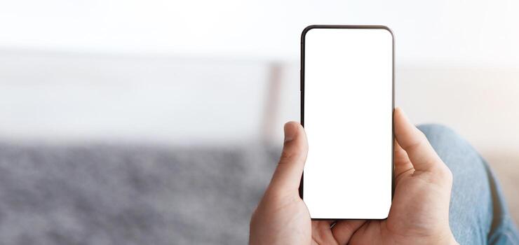 Mockup for website advertisement. Unrecognizable man using smartphone with blank screen, sitting at home, empty space, closeup. Guy making call, surfing internet or chatting in social networks photo