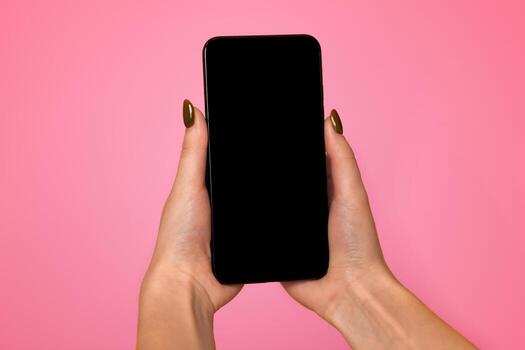 Modern smartphone with black blank screen for mockup in woman's hands on yellow studio background, top view with empty space. Free space for your text, logo or design photo
