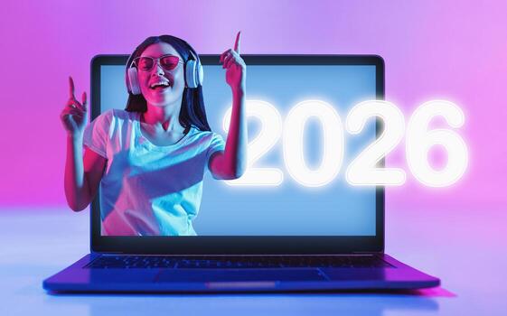 The scene features a laptop computer with a blank white screen illuminated by vibrant neon lights. This setup provides a modern graphic template for advertisements. photo