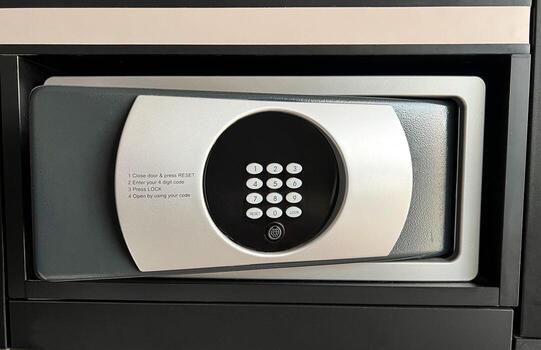 Electronic safe deposit box with digital keypad and instructions on the front panel. Modern hotel room or office security safe close-up, password protection system concept. photo