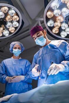 A surgeon performs an operation in a sterile operating room, with a surgical assistant observing. photo
