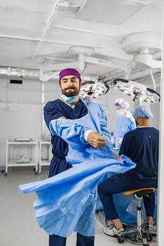 A surgeon is putting on a surgical gown in a modern operating room, preparing for a procedure with his team. photo