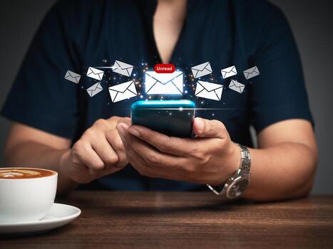 Close-up of a businessman using a mobile receive a new message with email icons while sitting at the table. photo