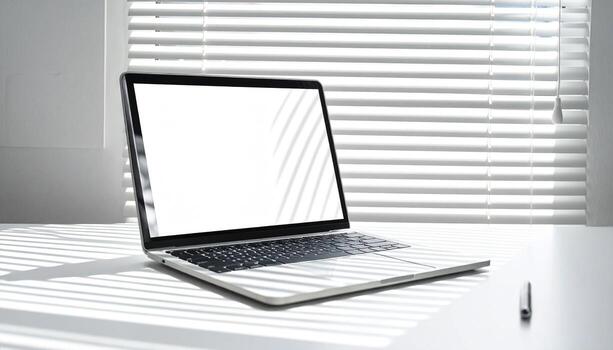 Laptop on a White Desk with Blinds Casting Shadows. photo