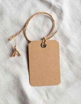Blank brown tag with string on white fabric background. photo
