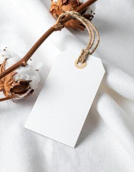 Elegant Cotton Branch with Blank Tag on White Fabric. photo