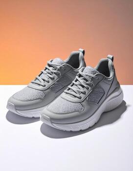 Stylish Gray Sneakers on White Surface with Orange Gradient Background. photo