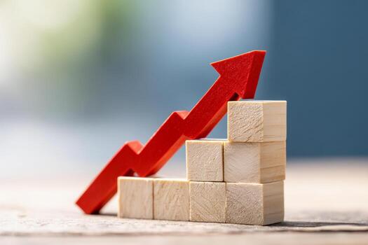 Wooden blocks arranged as ascending bars with a red arrow indicating growth and progress against a blurred background symbolizing business success and development photo