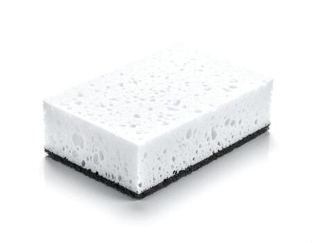 White sponge rests on a white surface, ready for cleaning tasks with its porous texture and contrasting black abrasive side, conveying cleanliness and utility. photo