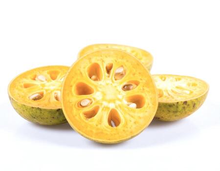 Sliced bael fruit displays its unique interior structure on a white surface, showcasing its seeds and segments in a simple, clean composition. photo