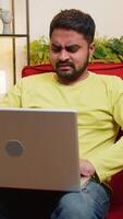 descontente triste indiano homem usar computador portátil caderno digitando navegando trabalhando, perde tornando-se surpreso de repente loteria resultados mau notícia fortuna perda jogos falhou computador vírus. árabe cara às casa quarto em cadeira video