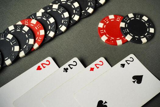 Four of a kind or quads playing cards lie on a grey table with black and red poker chips stacked next to them, creating an atmosphere of excitement photo