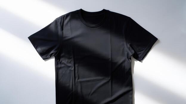 Black T Shirt Lying on White Surface With Light and Shadow Patterns photo