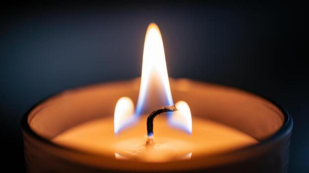 Close up of a Glowing Candle Flame Illuminating the Dark Room With a Warm Light photo