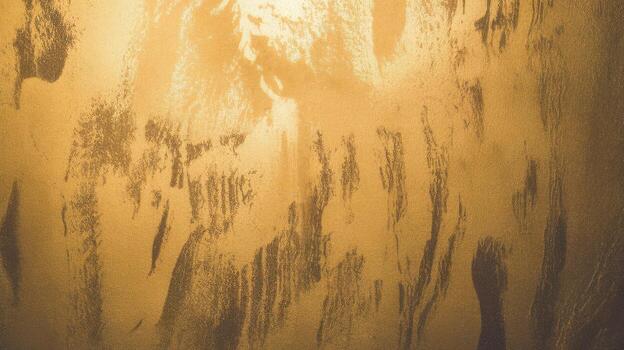 Gold Textured Surface Showing Dark Brushstrokes and Variations in Tone photo