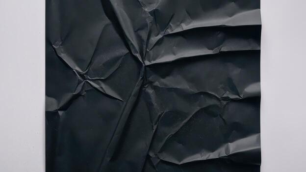 Crumpled Black Paper Sheet on a White Surface Creates Texture photo