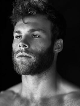 A man with a beard and a mustache is standing in front of a black background photo