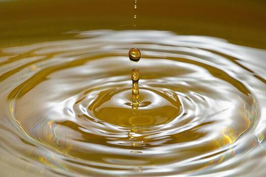 A drop of oil is falling into a bowl of water photo