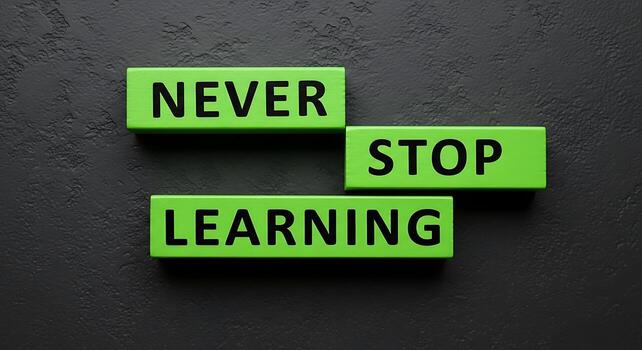 Never Stop Learning inspirational message on green blocks against a dark textured background photo