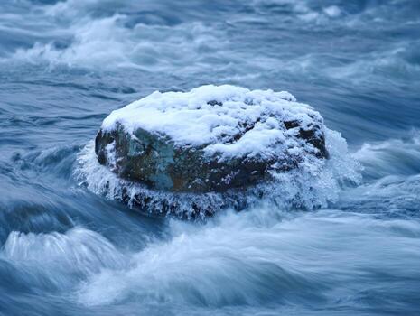 The Stillness of a Snowy Rock in a Flowing River photo