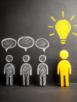 Conceptual image of a group with chalk-drawn figures sharing speech bubbles contrasted by a highlighted figure with a glowing light bulb representing a bright idea and leadership photo