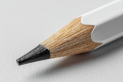 Detailed macro view of a sharpened wooden pencil tip with smooth graphite core against a clean gray surface showing texture and craftsmanship in stationery design photo