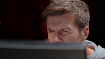 de cerca de hombre poniendo en lentes y mirando a computadora pantalla mientras trabajando a noche video