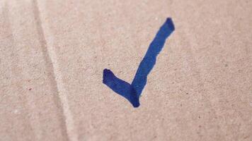 kolla upp märke, bock, en hand teckning en kolla upp mark med en blå markör på brun papper, symboliserar Framgång, godkännande, och korrekt beslutsfattande, närbild video