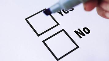 Vote, Hand using a blue marker to draw a check mark in the Yes box on a questionnaire, symbolizing approval, agreement, or positive decision, close-up video