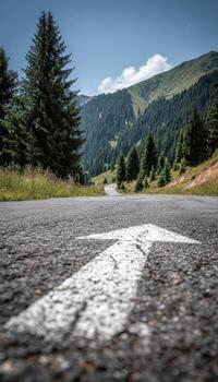 Winding mountain road with arrow pointing forward in lush green forest and hills photo