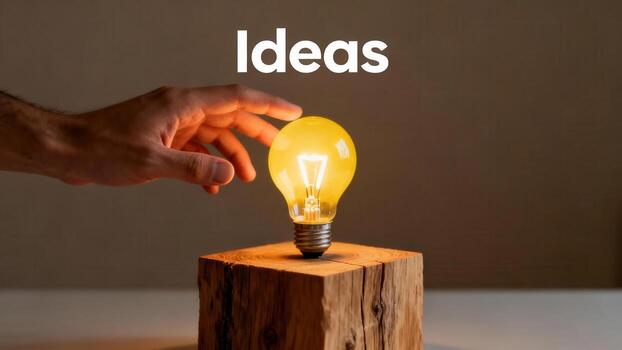 A hand reaches for a warm-hued light bulb nestled on a rustic wooden block, suggesting new ideas. photo